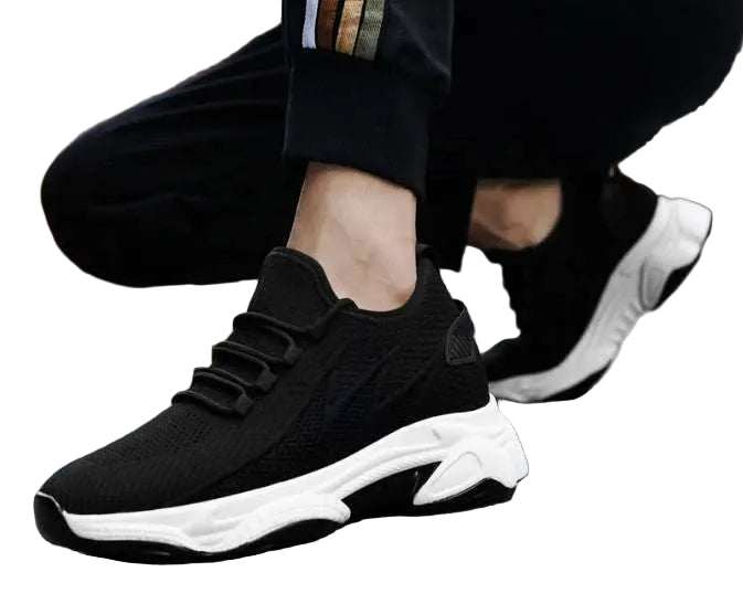Black golf trainers with white soles worn by a person on a street.