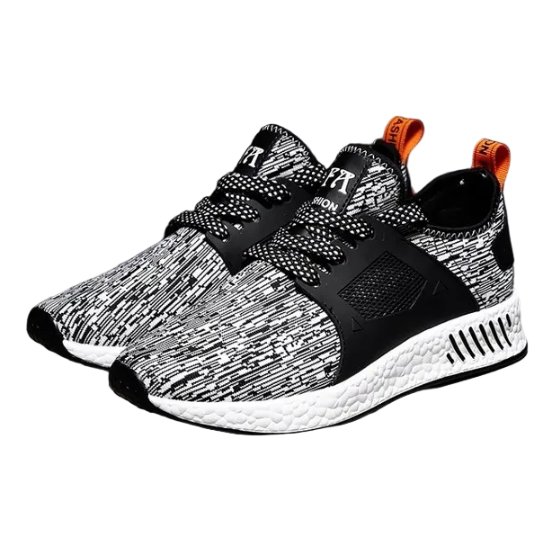 Black and white patterned golf trainers with orange accents on a dark background