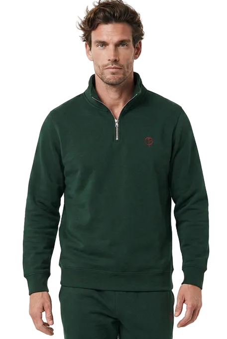 A man modeling a dark green quarter-zip golf jumper and matching sweatpants set, paired with white sneakers, against a plain white studio background.