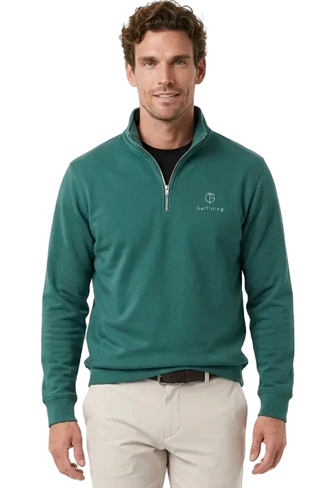 A man modeling a dark green quarter-zip golf jumper paired with beige trousers and white golf shoes, against a plain white studio background.