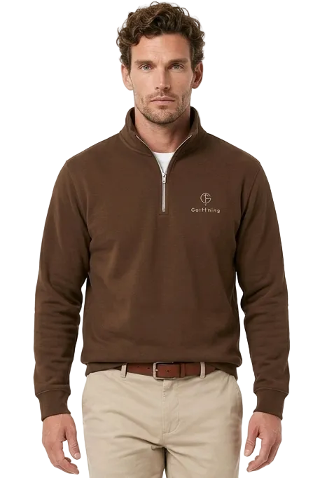 A man modeling a brown quarter-zip golf sweater with a small embroidered logo on the left chest, paired with beige golf trousers and brown shoes, against a plain white studio background.