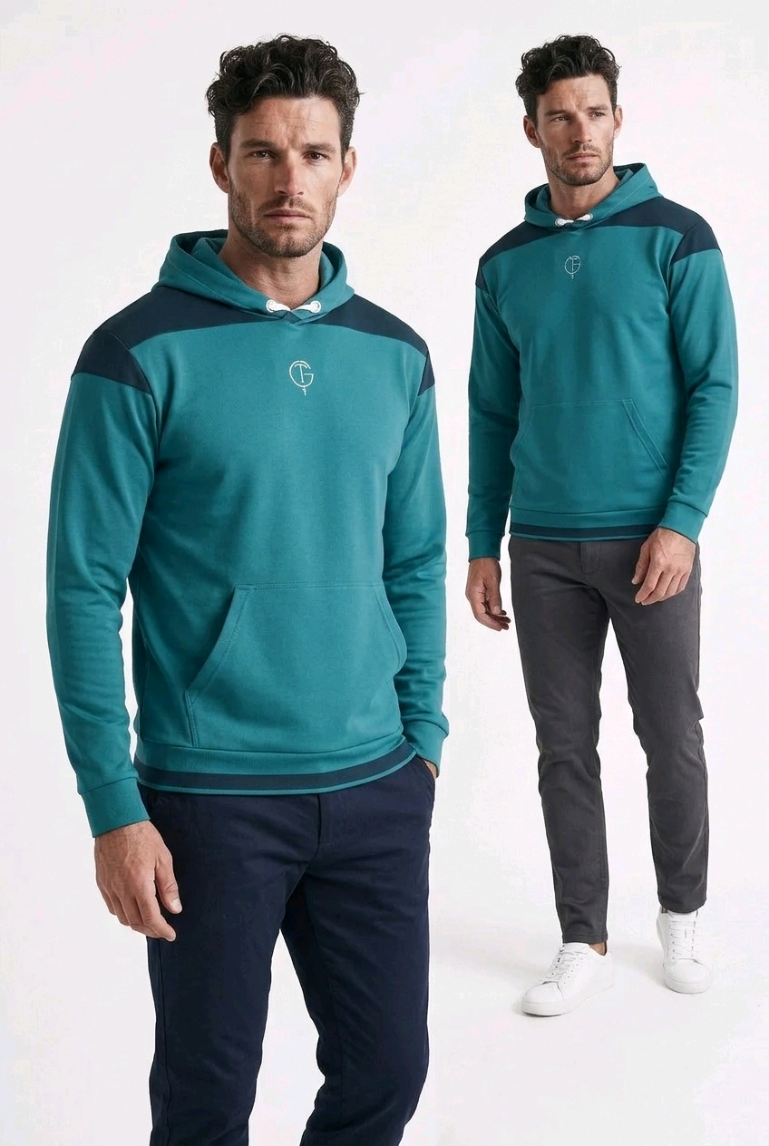 Two male models wearing matching teal and navy blue color-blocked golf hoodies, standing against a plain white studio background.