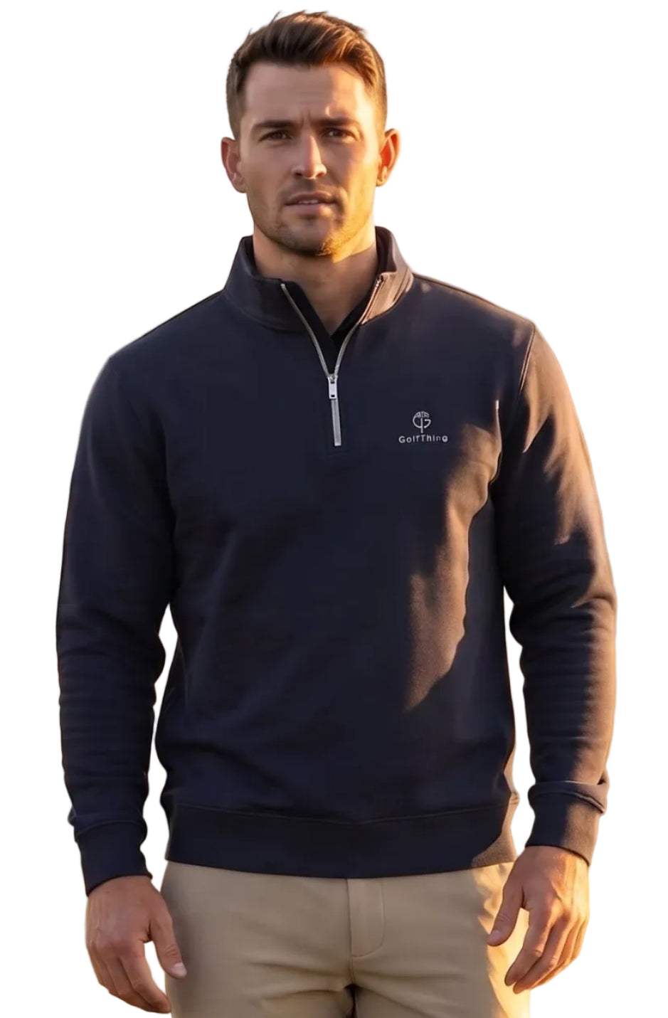 A man standing on a golf course wearing a navy blue quarter-zip golf jumper with a small white embroidered logo on the left chest, khaki pants, and white golf shoes.